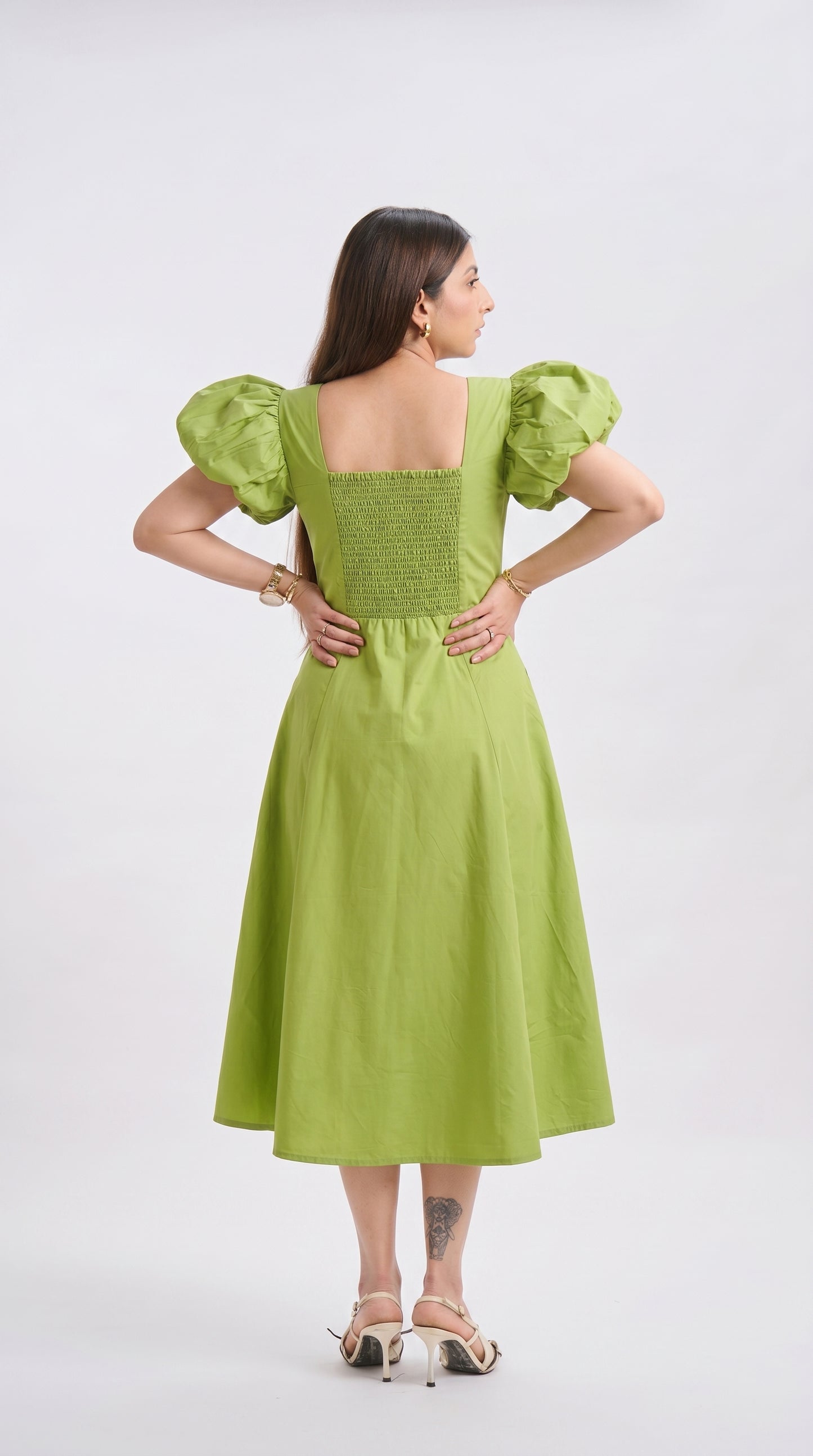 Woman wearing a green dress with puffed sleeves on a white background