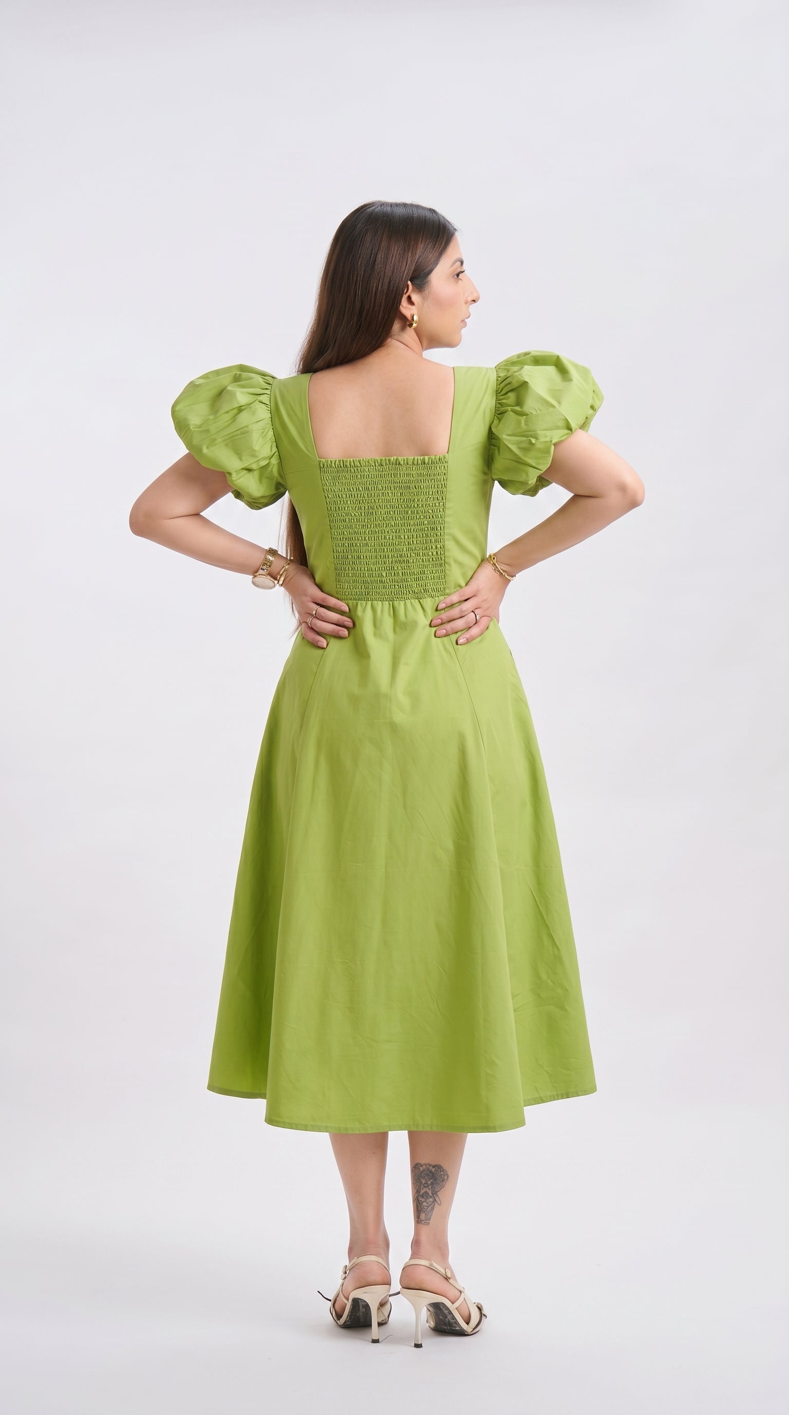 Woman wearing a green dress with puffed sleeves on a white background