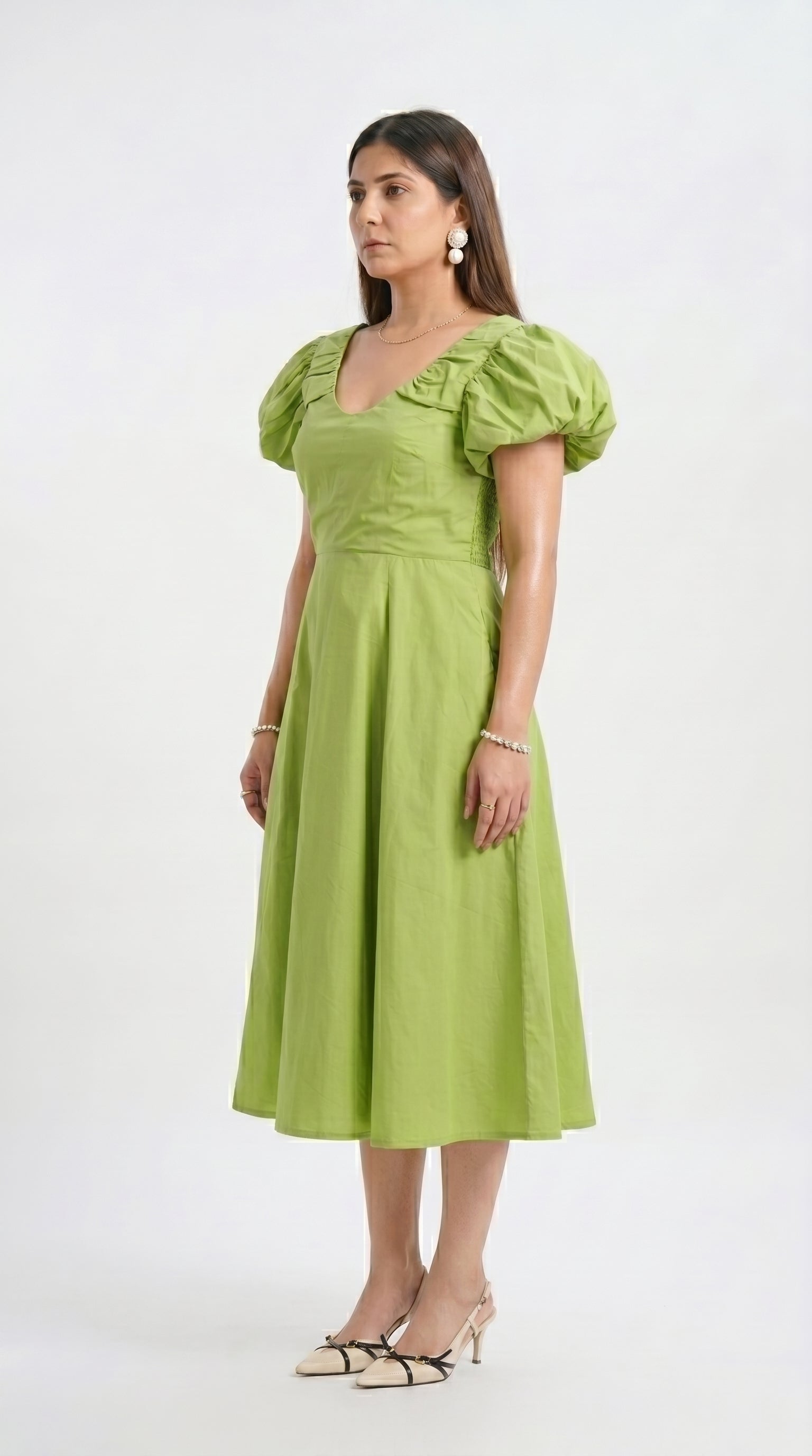 Woman wearing a green dress with puff sleeves on a white background