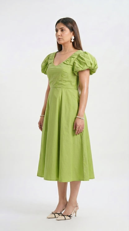 Woman wearing a green dress with puff sleeves on a white background