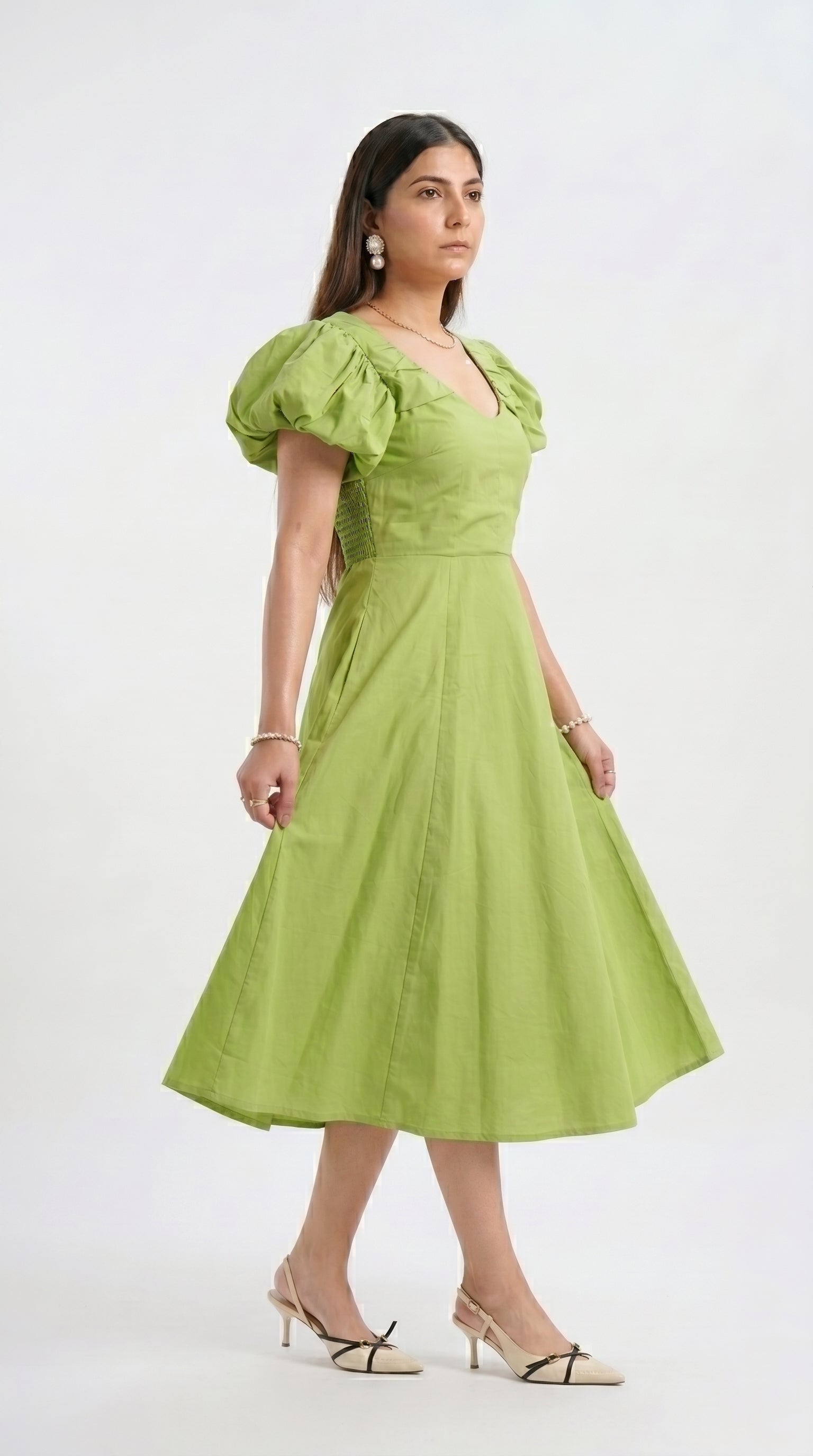 Woman wearing a green dress with puff sleeves on a white background