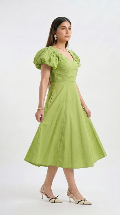 Woman wearing a green dress with puff sleeves on a white background