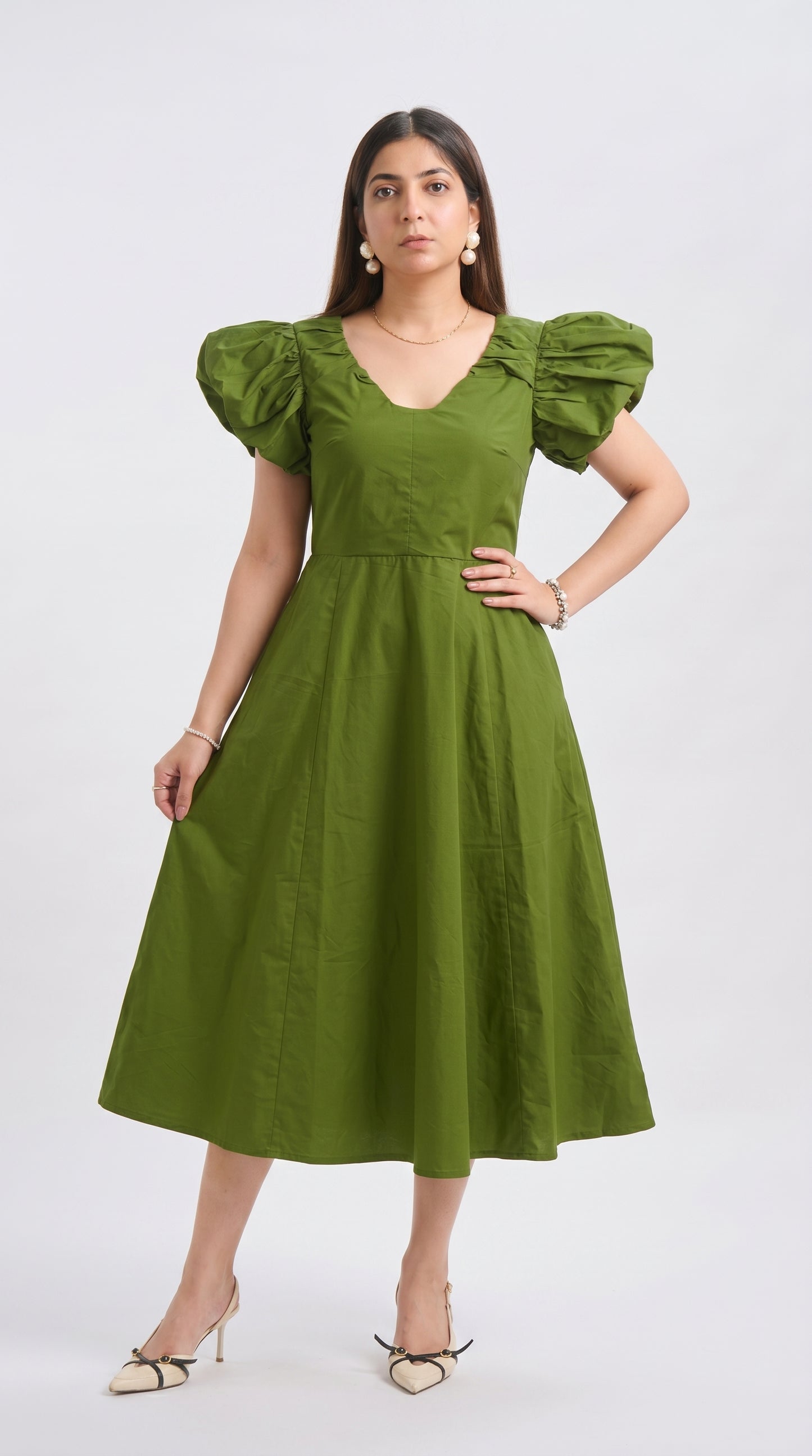 Woman wearing a green dress with puffed sleeves on a white background