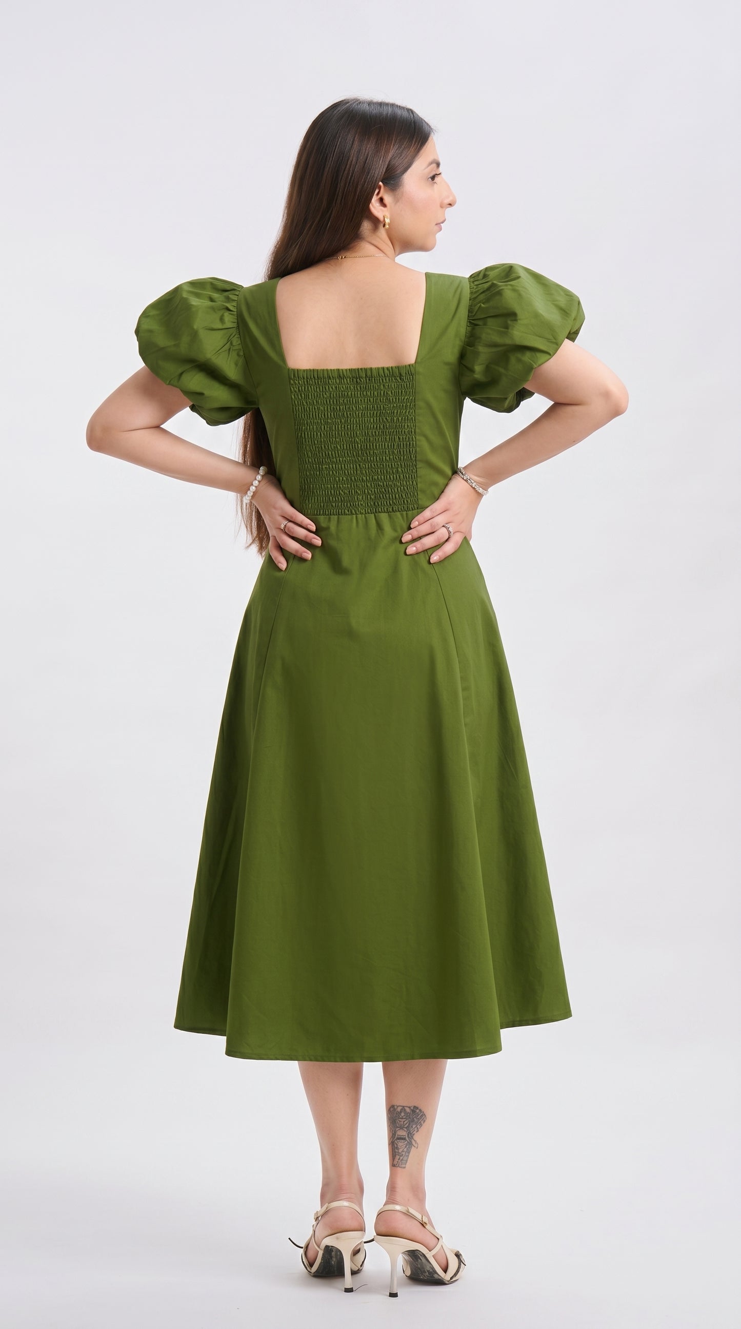 Woman wearing a green dress with puffed sleeves on a white background