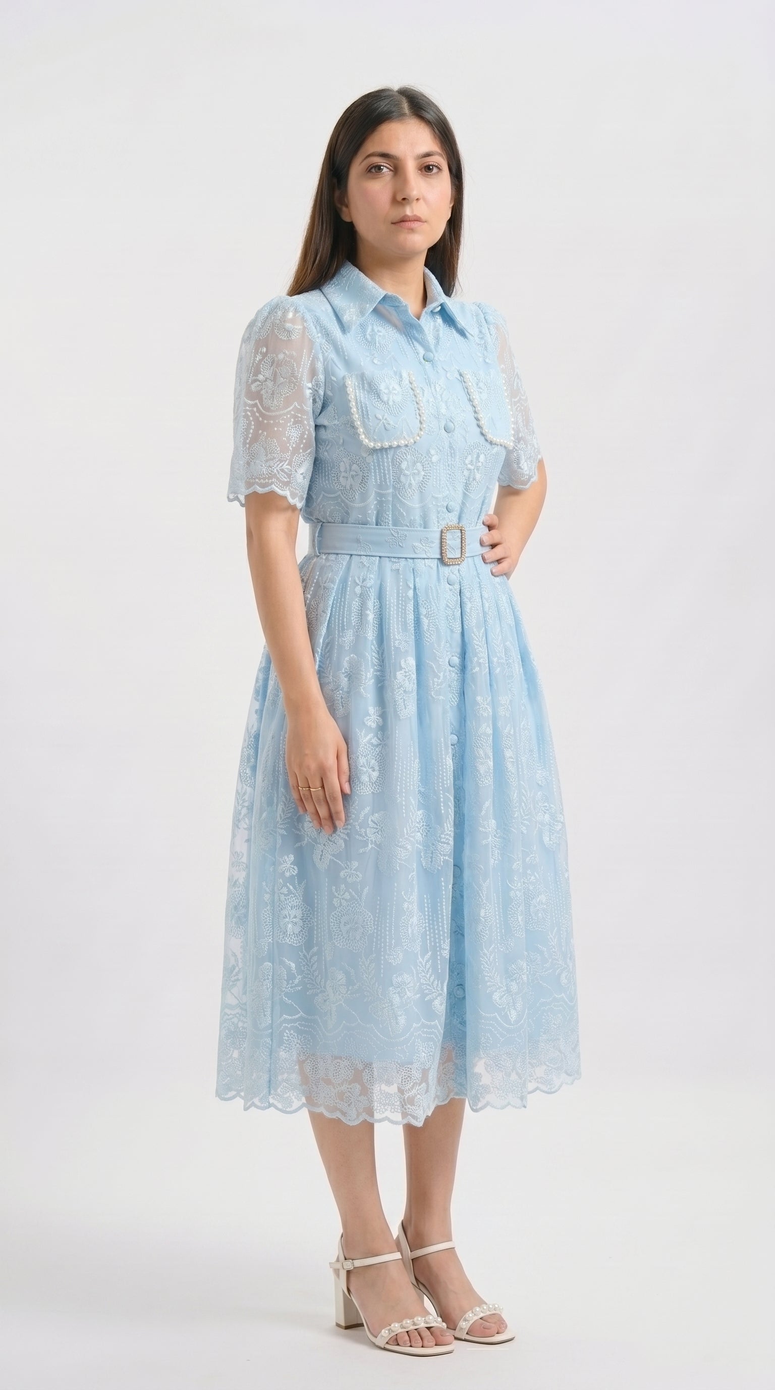 Woman wearing a light blue dress with a belt on a white background