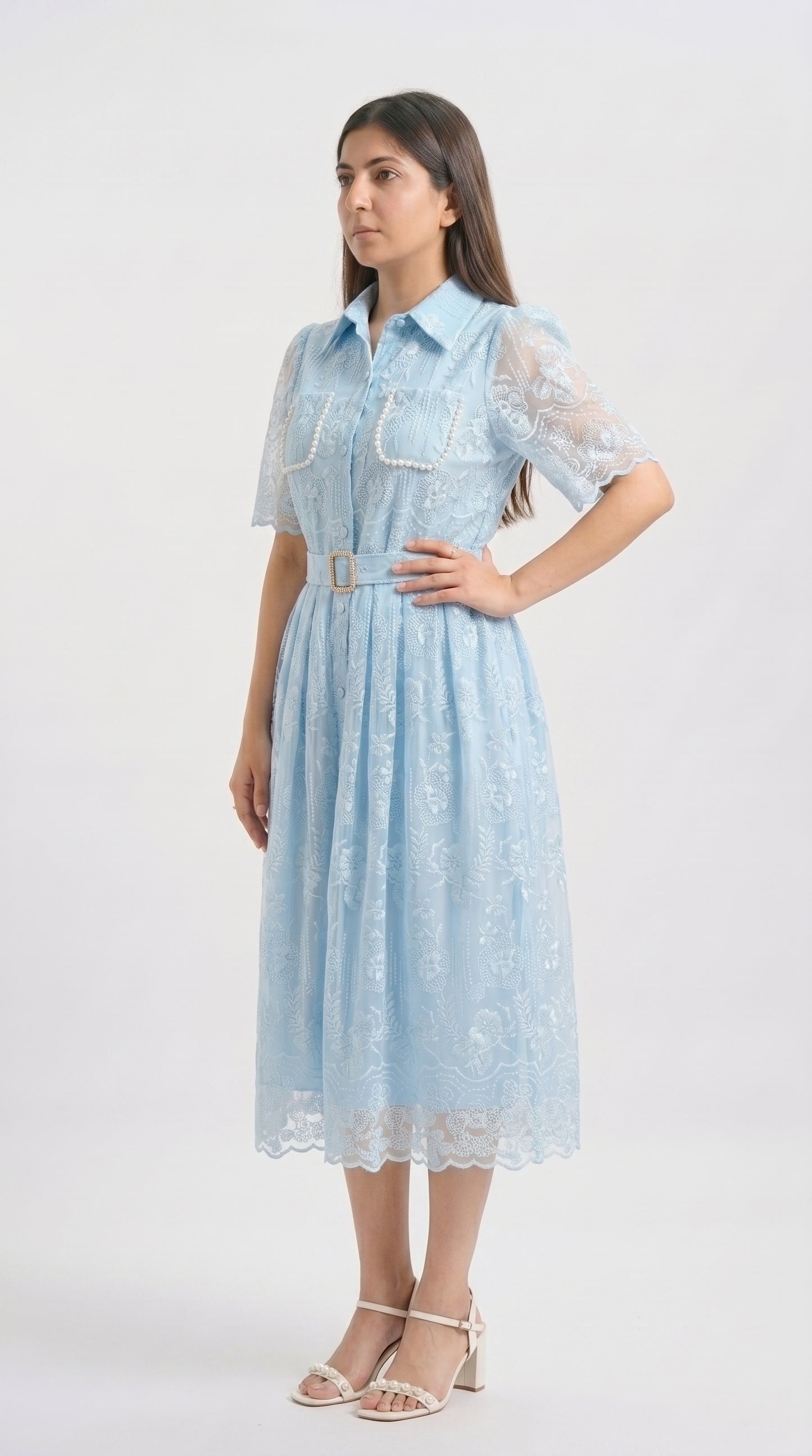 Woman wearing a light blue dress with lace details on a white background