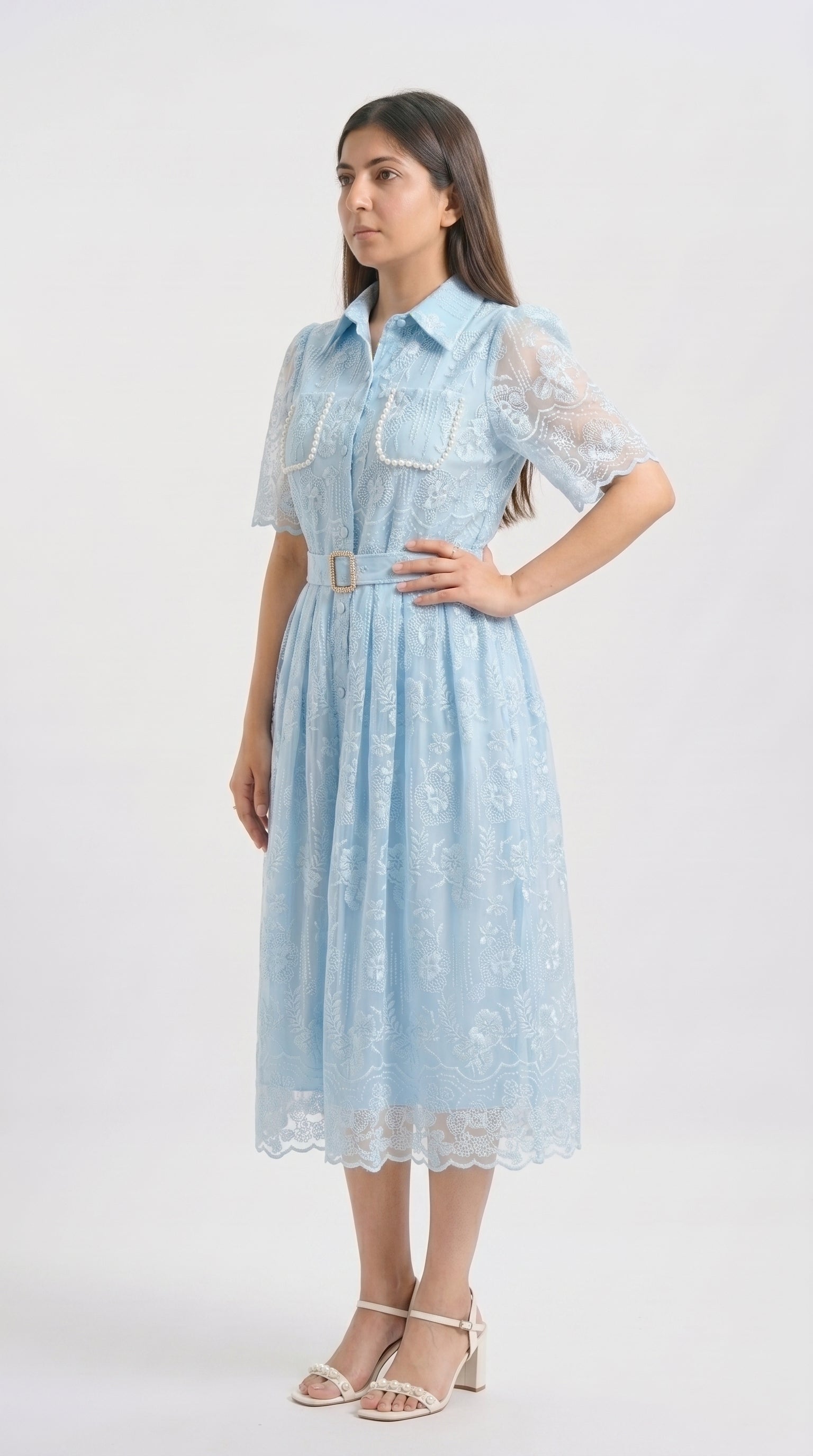 Woman wearing a light blue dress with lace details on a white background