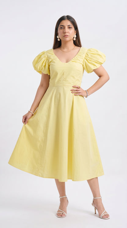 Woman wearing a yellow dress with puff sleeves on a white background