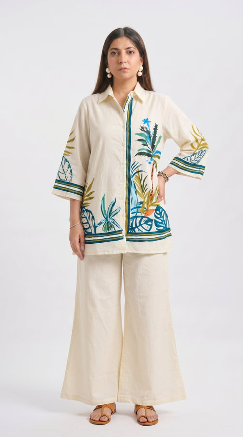 Woman wearing a cream outfit with floral embroidery on a white background