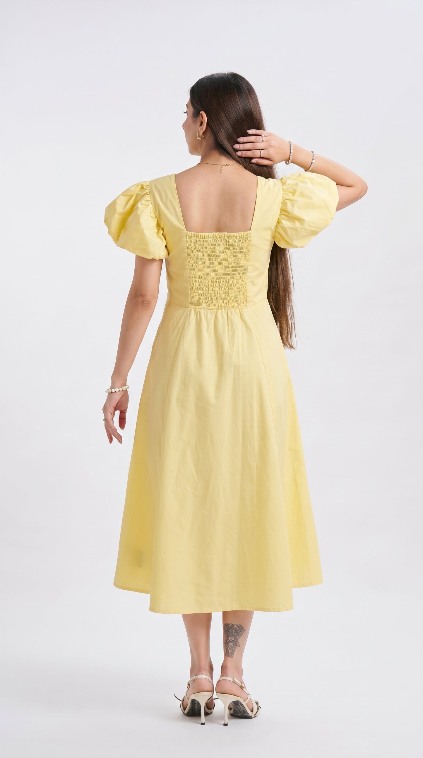 Woman wearing a yellow dress with puffed sleeves on a white background