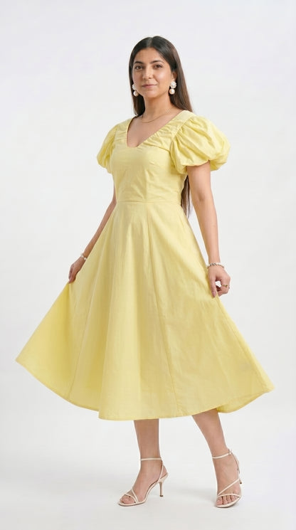 Woman wearing a yellow dress with puff sleeves on a white background