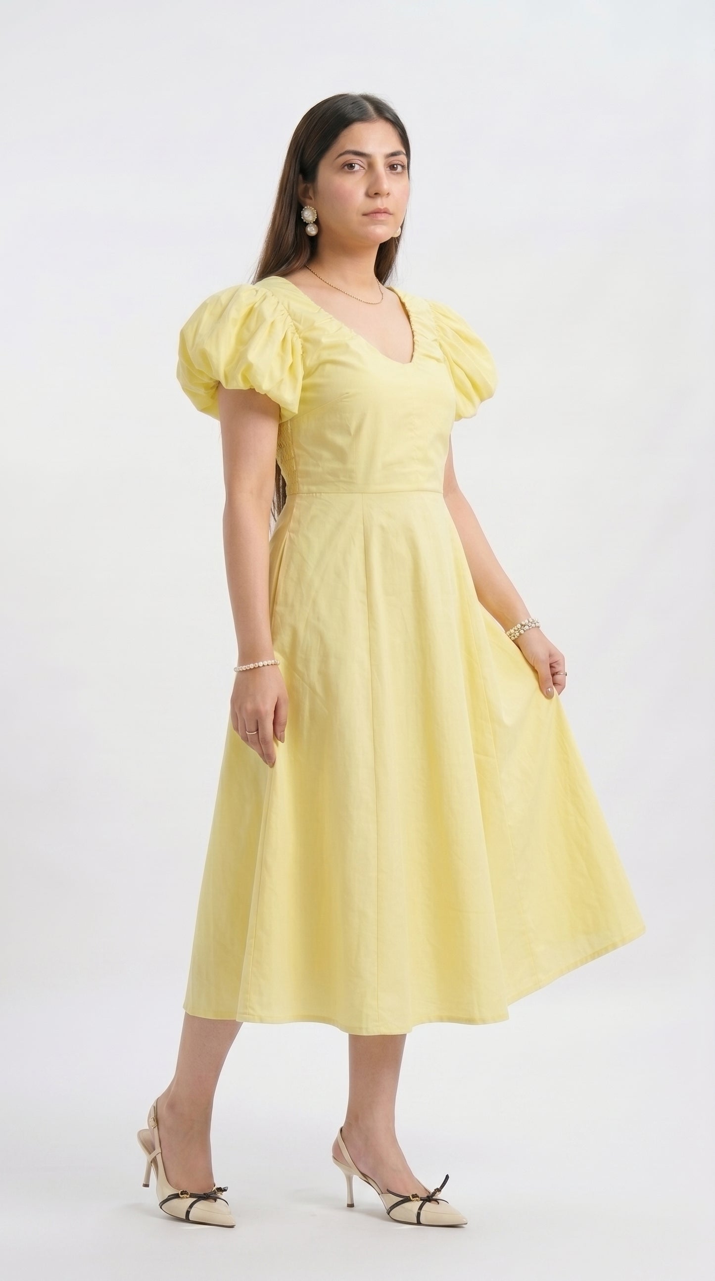 Woman wearing a yellow dress with puff sleeves on a white background