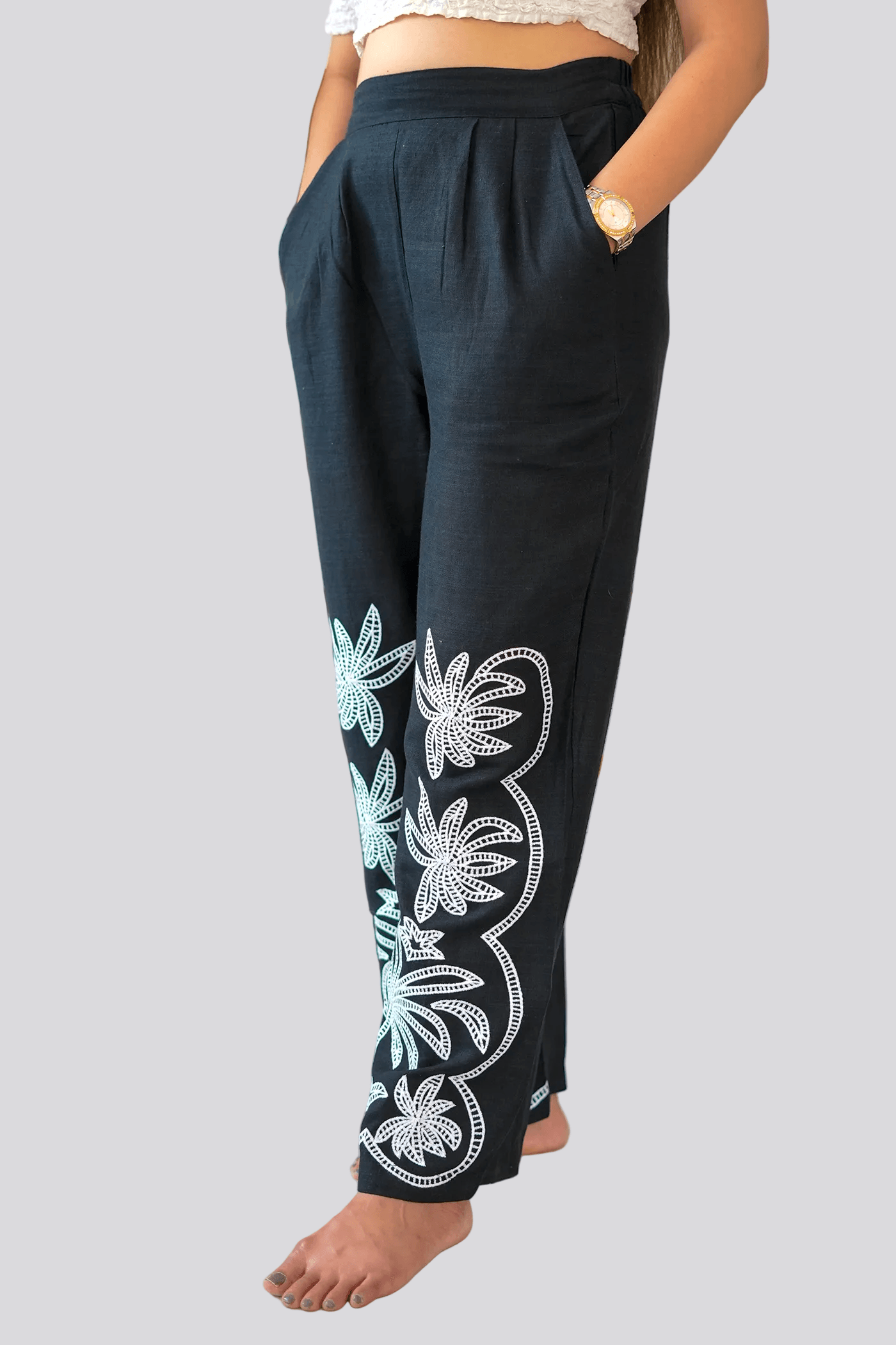 Black pants with floral embroidery on a plain background
