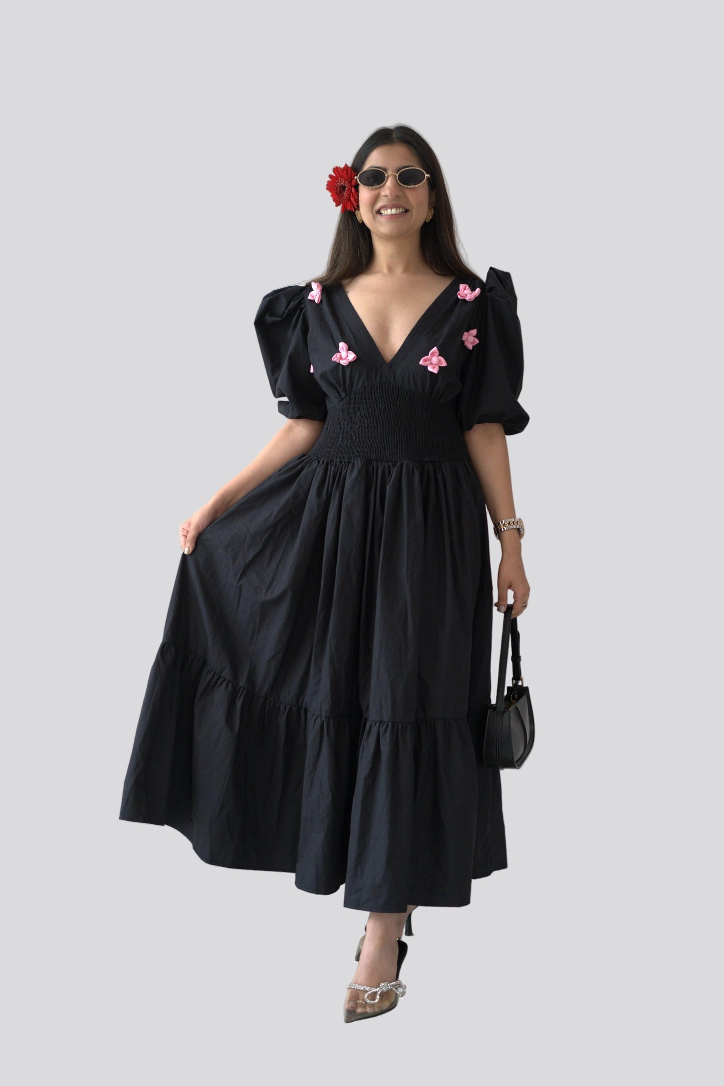 Woman wearing a black dress with pink butterfly details against a white background