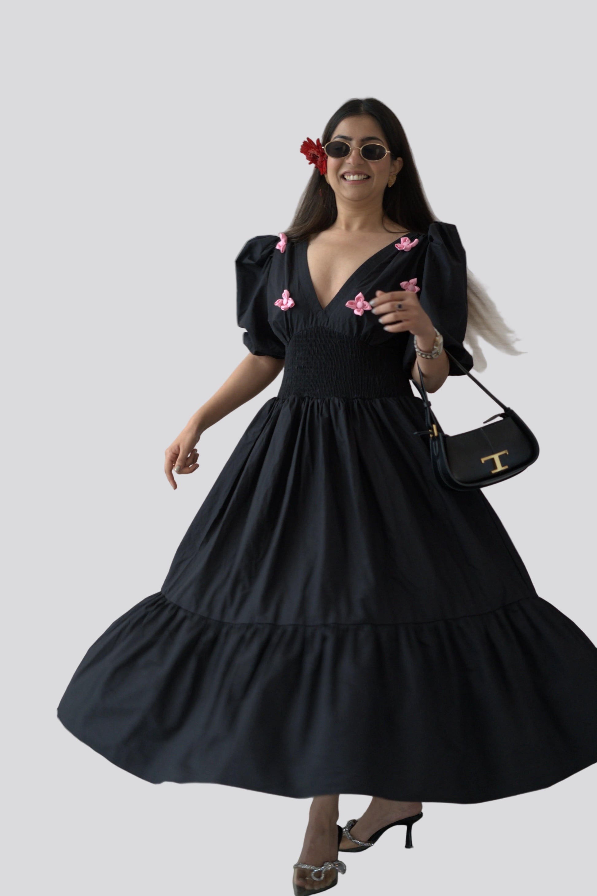 Woman wearing a black dress with pink floral accents against a white background
