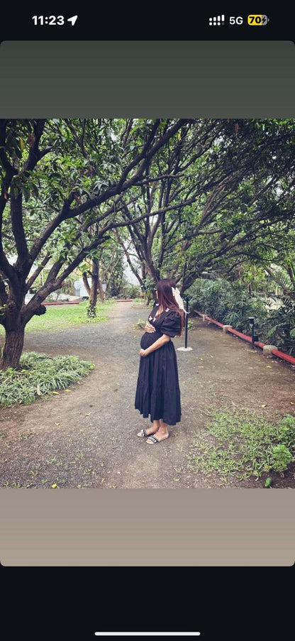 Woman in a black dress standing on a path surrounded by trees