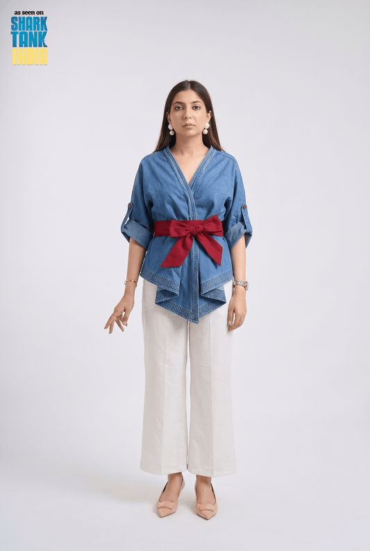 Woman wearing a blue shirt with a red belt and white pants on a white background
