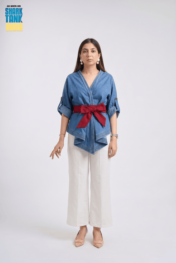 Woman wearing a blue shirt with a red belt and white pants on a white background
