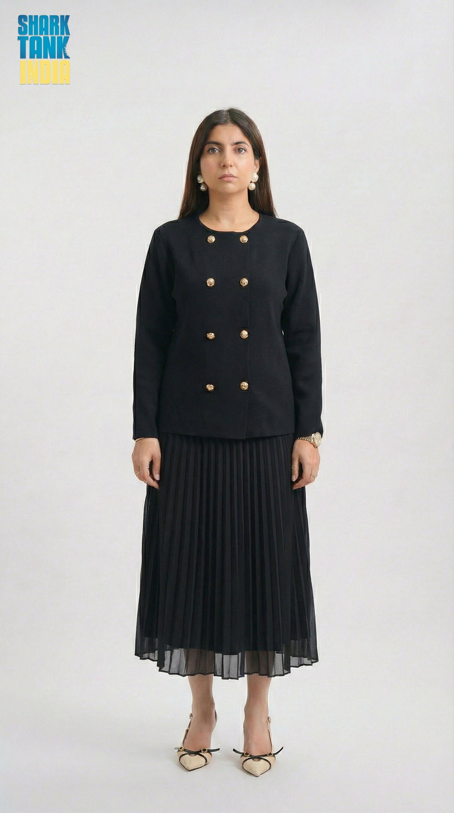 Woman wearing a black outfit with gold buttons on a white background