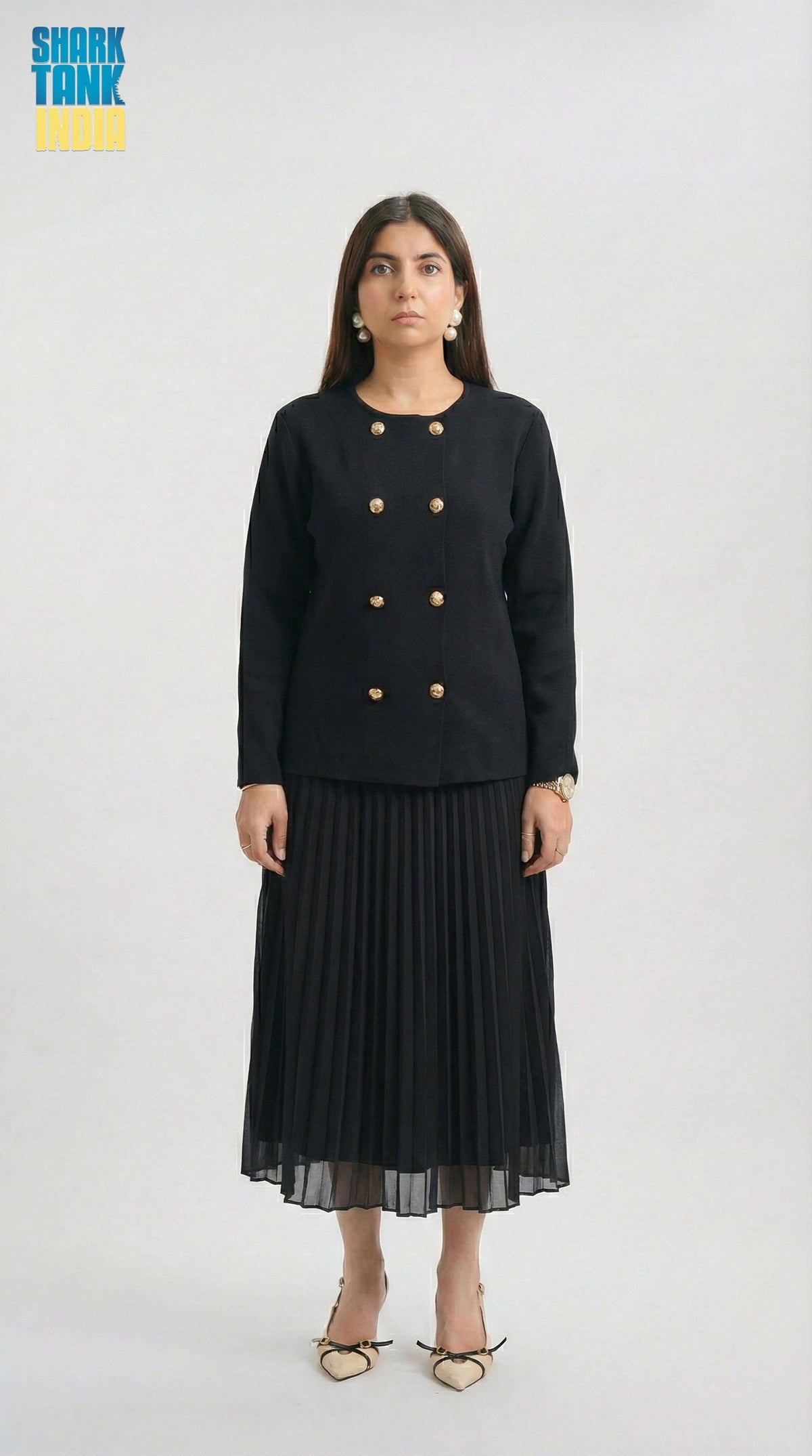 Woman wearing a black outfit with gold buttons on a white background