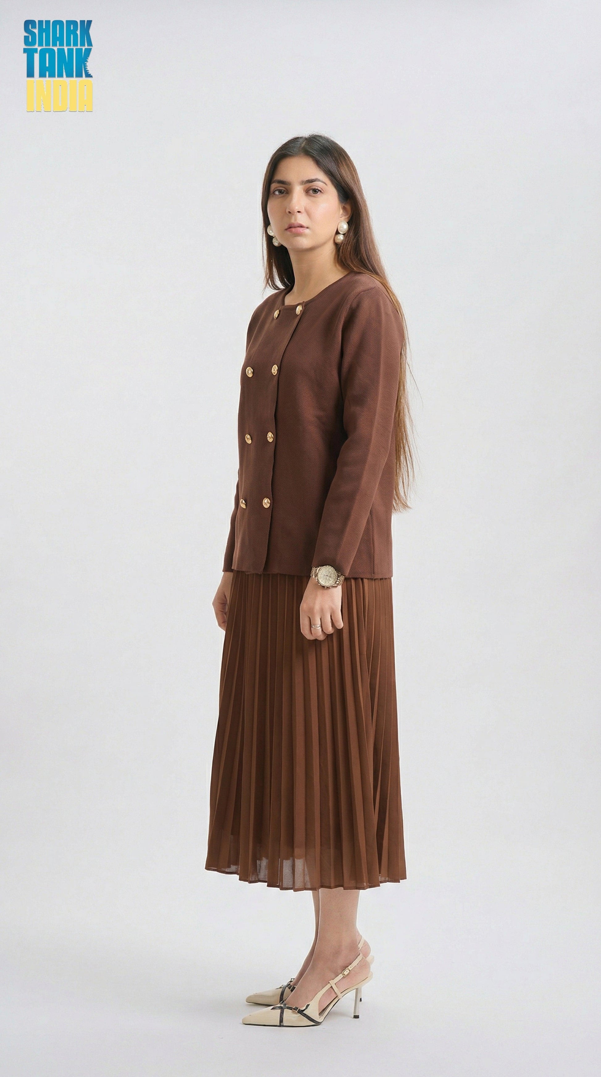 Woman wearing a brown suit with a pleated skirt on a white background