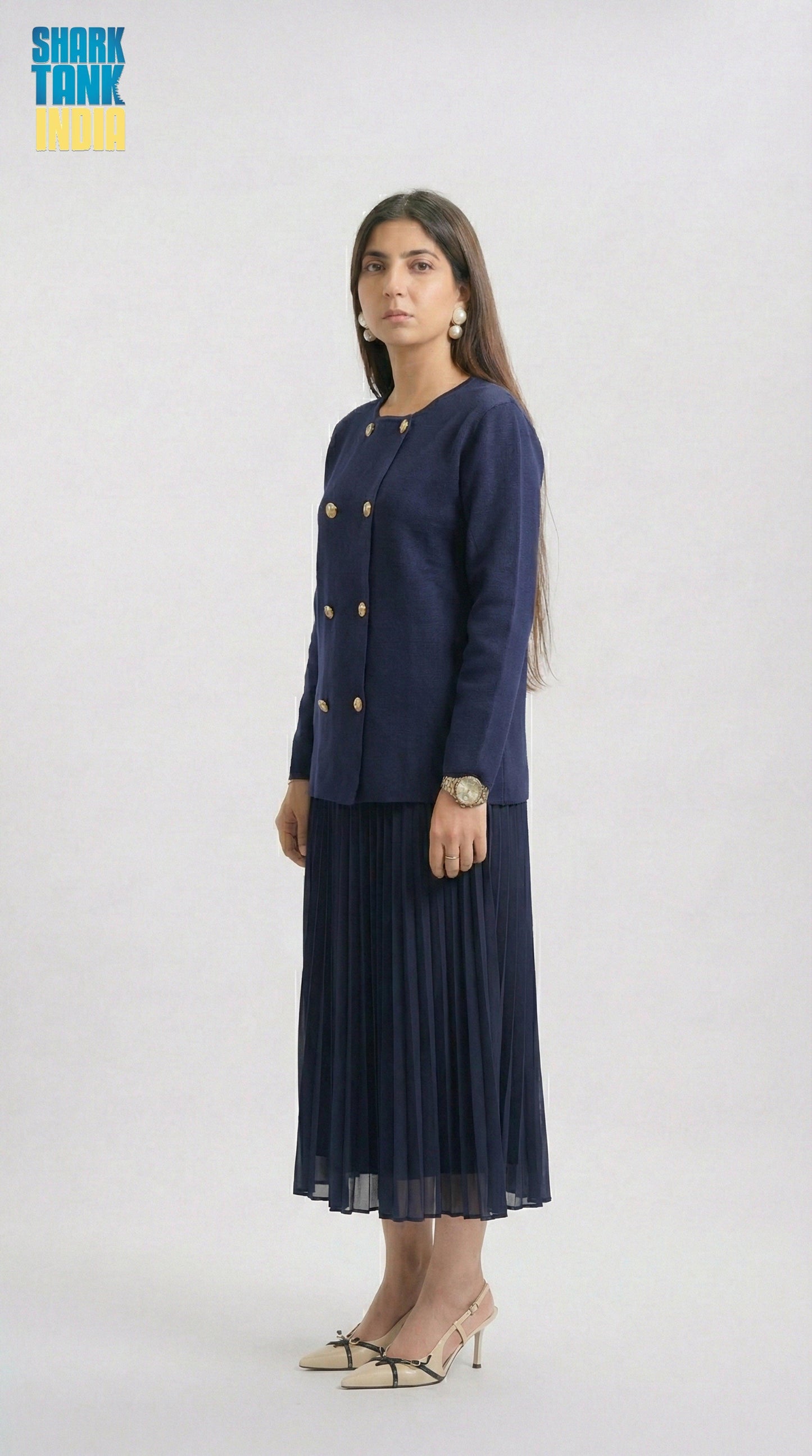 Woman wearing a navy blue suit with gold buttons on a white background