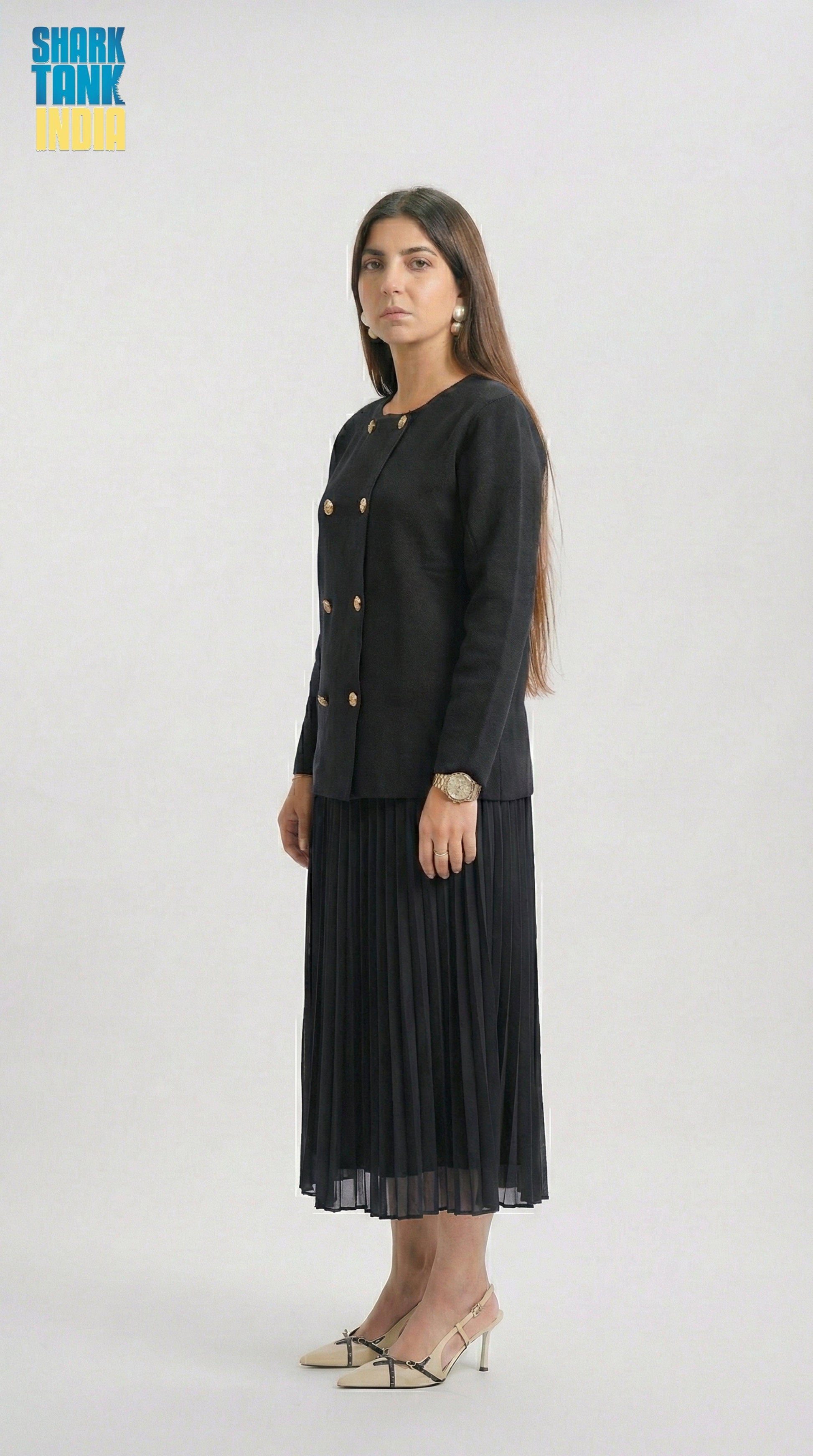 Woman wearing a black outfit with gold buttons on a white background