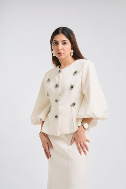 Woman wearing a cream-colored outfit with floral embellishments on a white background