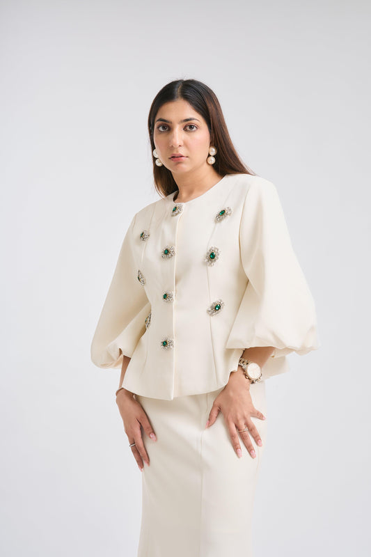 Woman wearing a cream-colored outfit with floral embellishments on a white background