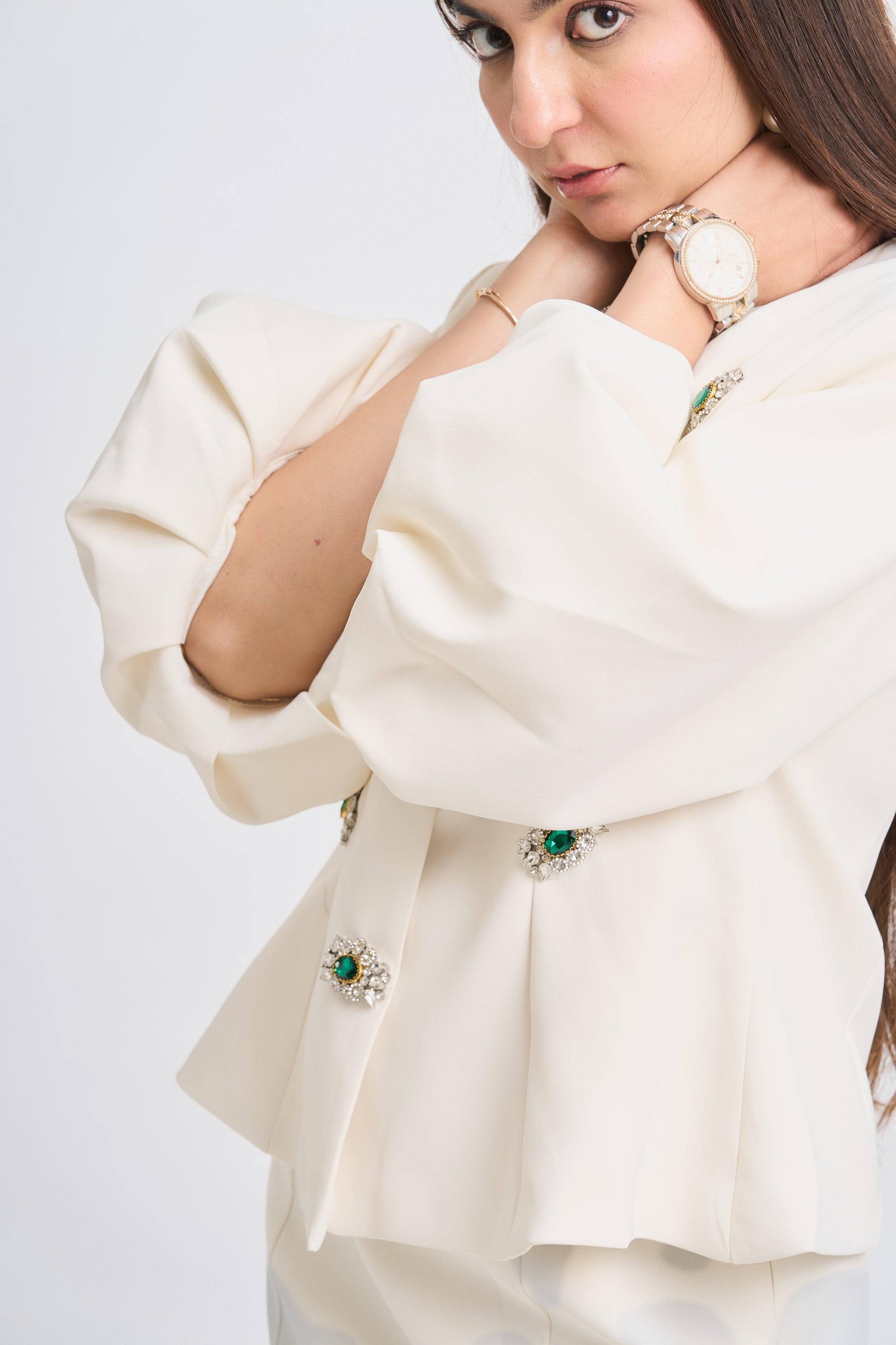 Woman wearing a cream-colored outfit with green embellishments on a white background