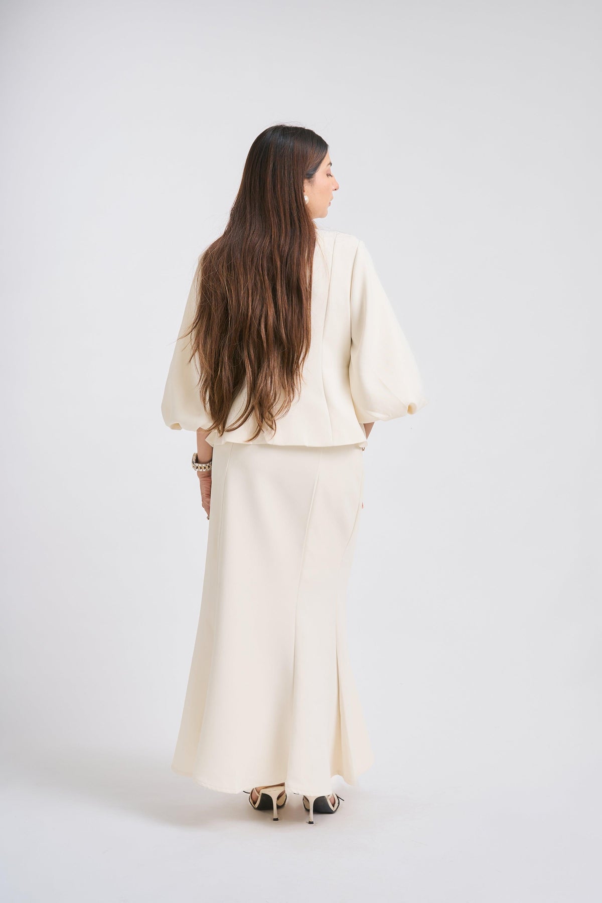 Woman wearing a cream-colored outfit against a white background