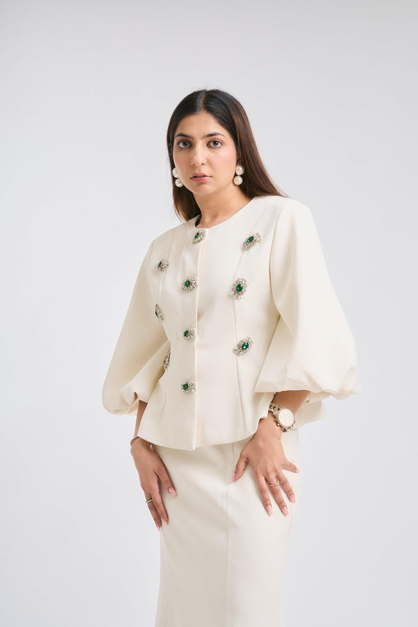 Woman wearing a cream-colored outfit with floral embellishments on a white background