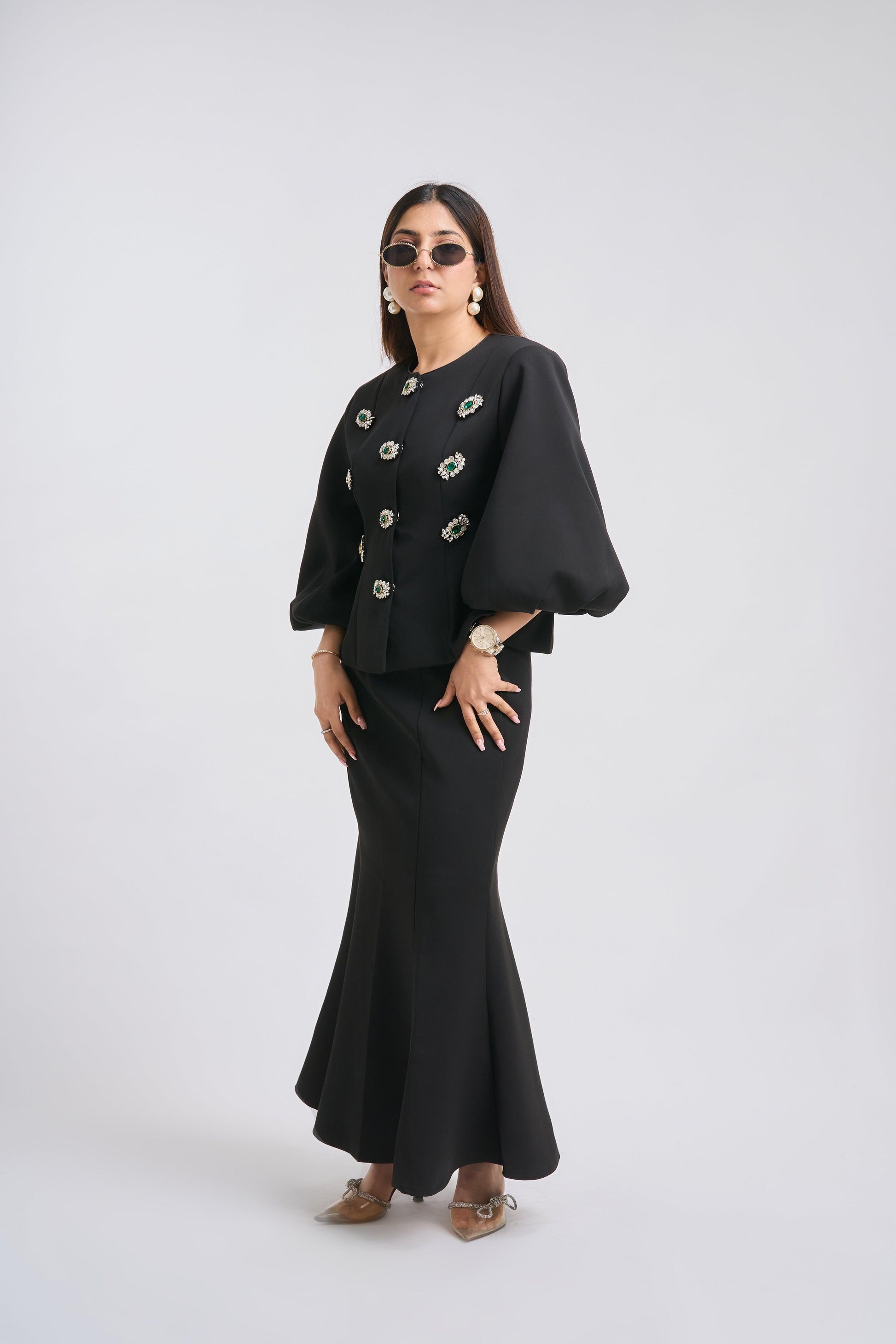 Woman wearing a black outfit with a jacket and skirt on a white background