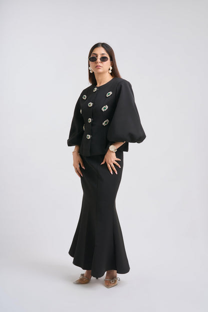 Woman wearing a black outfit with a jacket and skirt on a white background