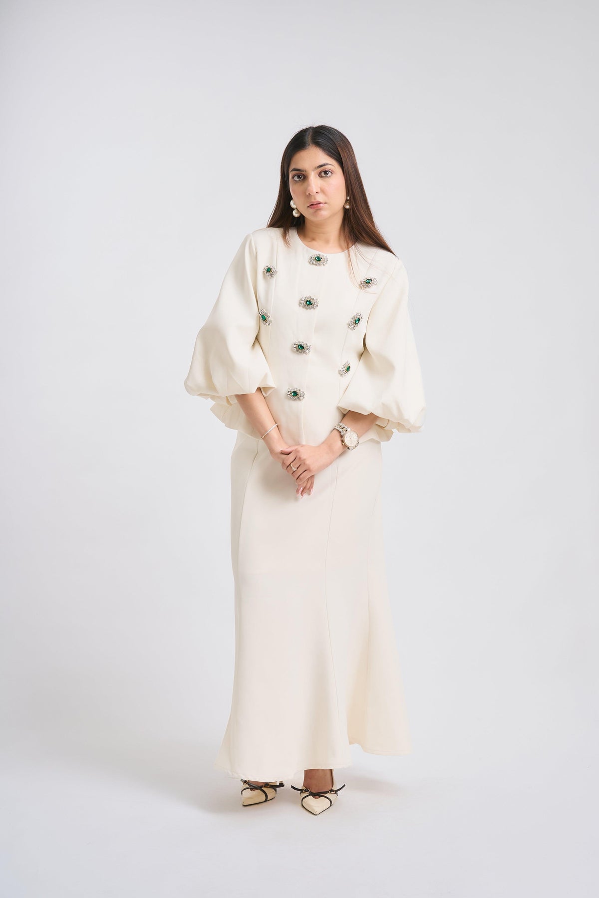 Woman wearing a white outfit with black buttons on a white background