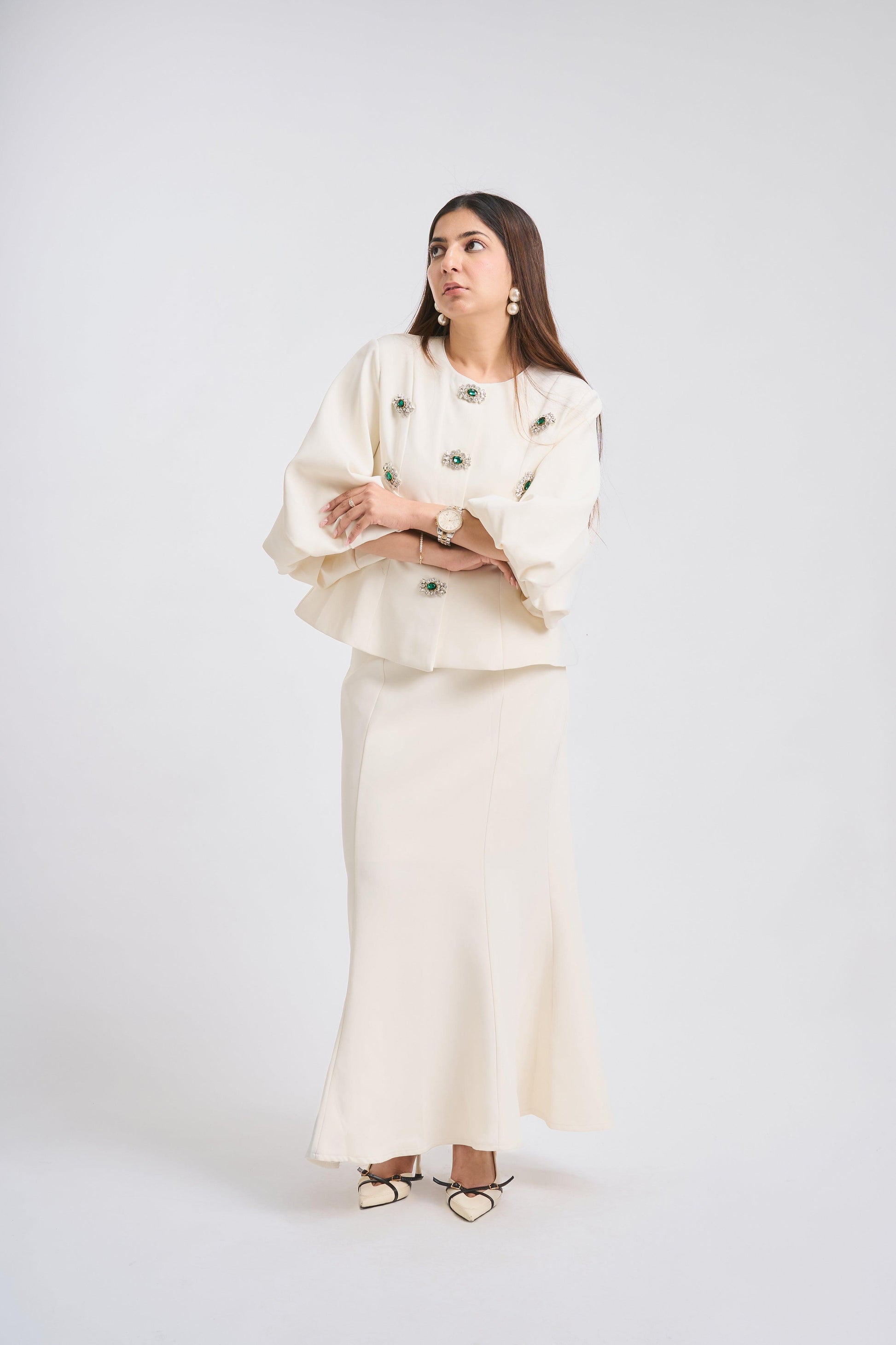 Woman wearing a white outfit with green buttons on a white background