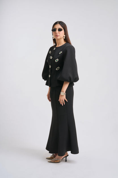 Woman wearing a black outfit with floral embellishments on a white background