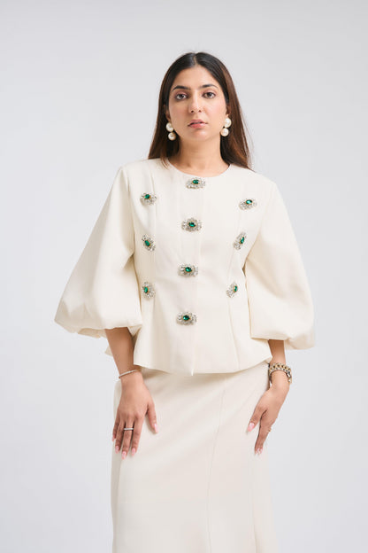 Woman wearing a white outfit with green embellishments on a white background