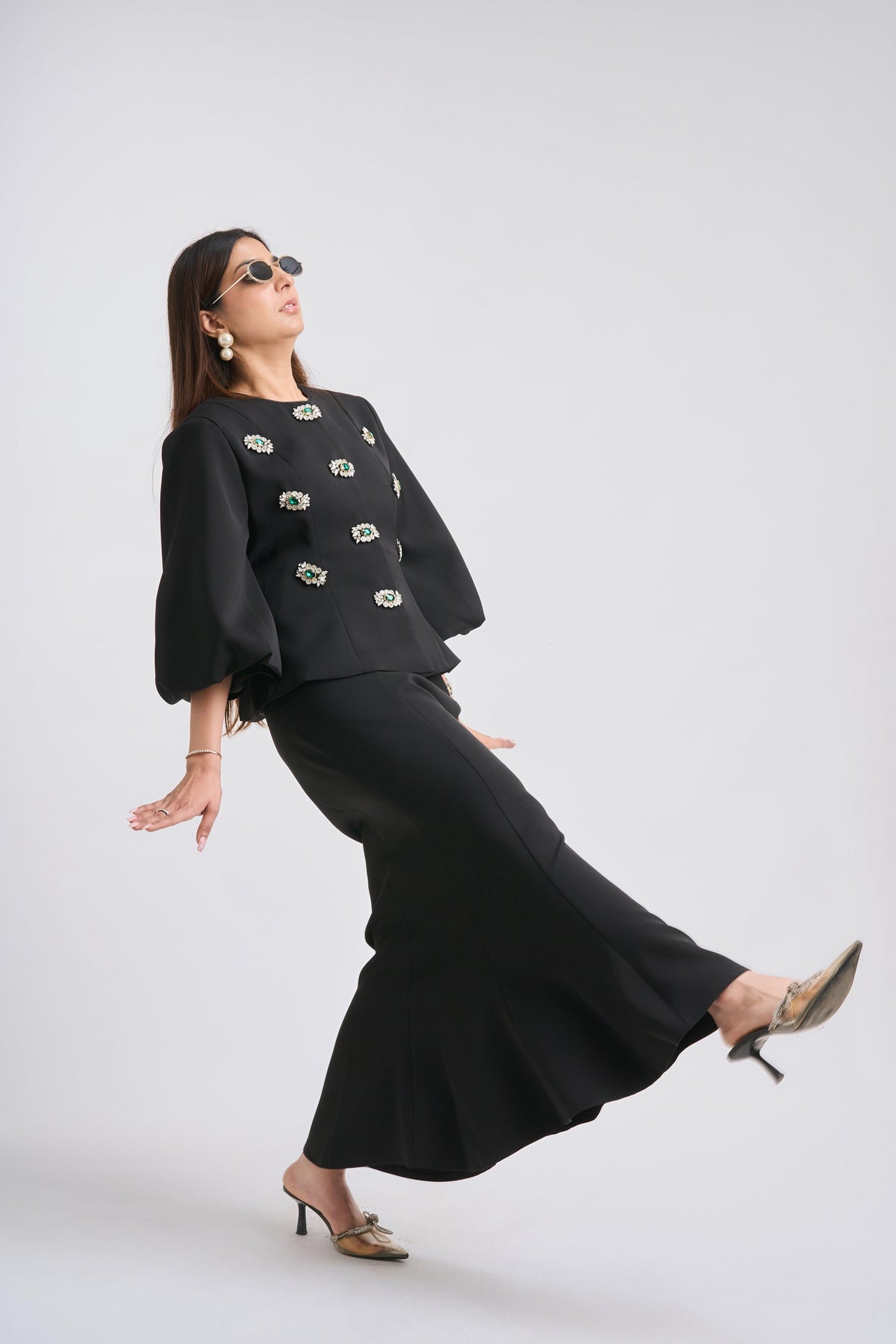 Woman wearing a black outfit with floral embellishments on a white background