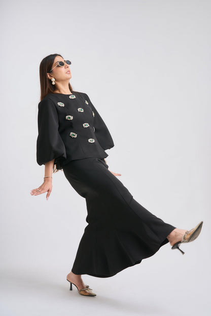 Woman wearing a black outfit with floral embellishments on a white background