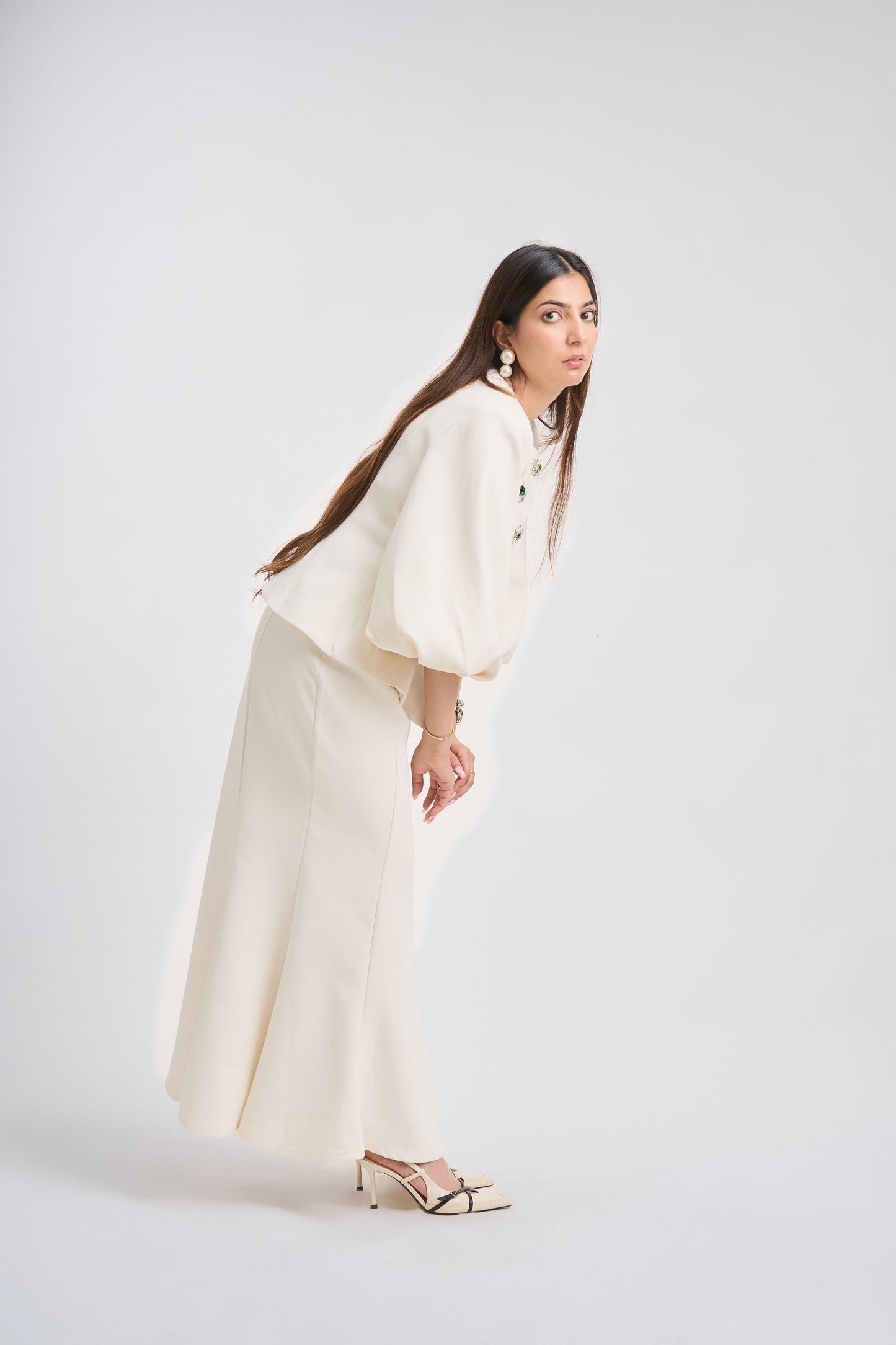 Woman wearing a white outfit with long sleeves and wide-leg pants on a white background
