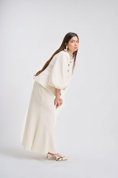 Woman wearing a white outfit with long sleeves and wide-leg pants on a white background