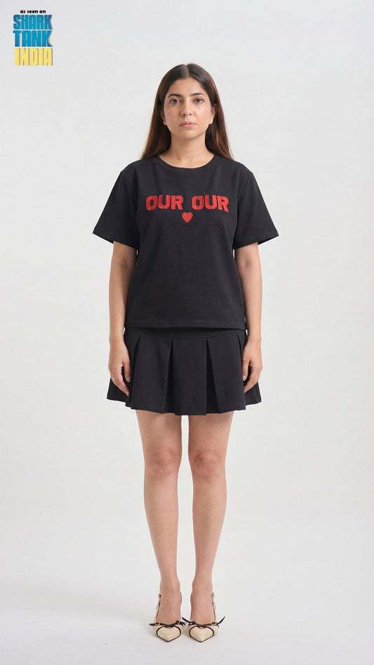 Person wearing a black t-shirt with 'OUR' printed on it, standing against a white background.