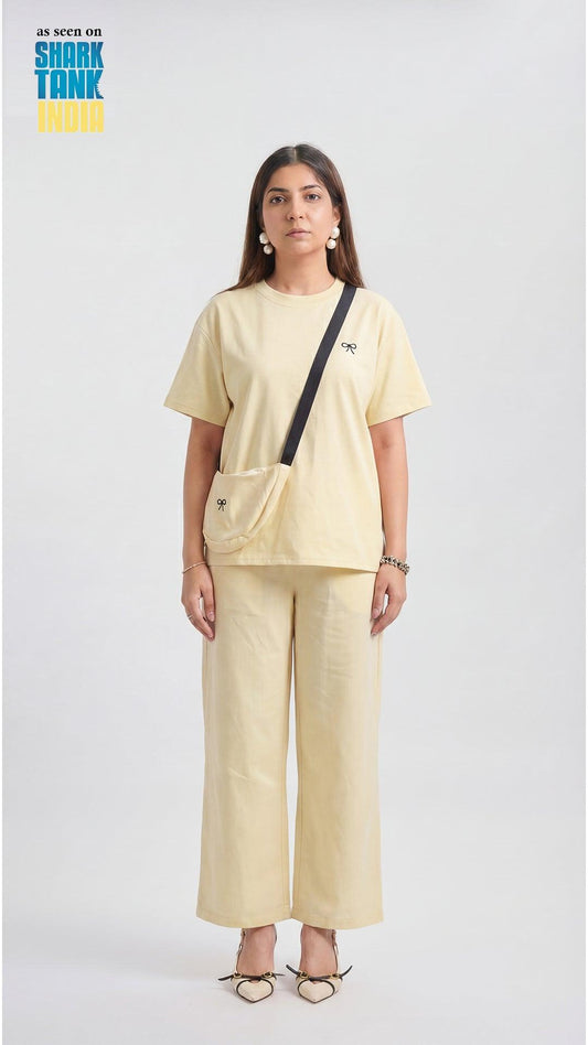 Woman wearing a beige outfit with a black crossbody bag on a white background
