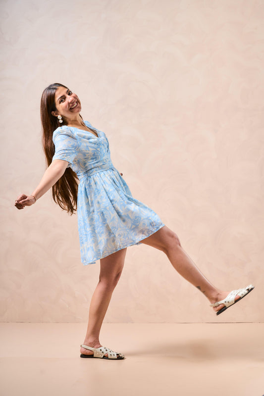 Woman in a light blue floral dress posing against a beige background