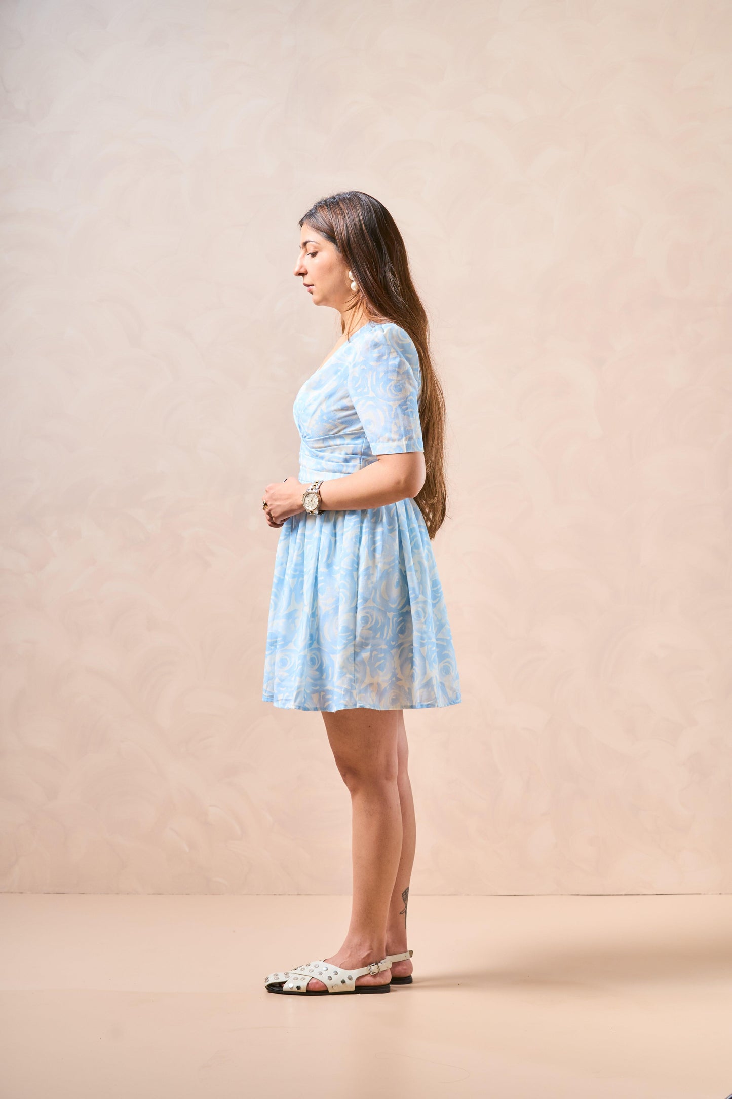 Woman wearing a light blue lace dress against a beige background