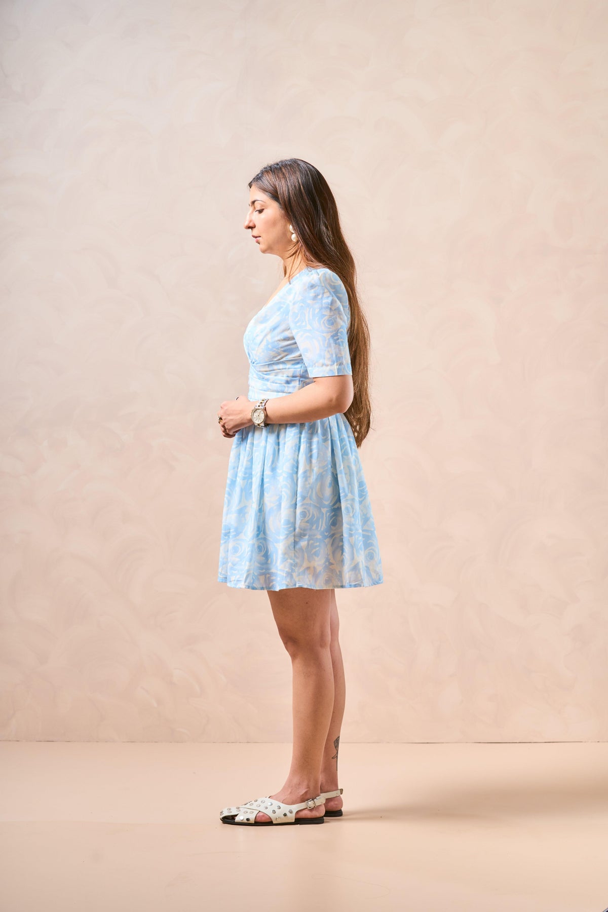 Woman wearing a light blue lace dress against a beige background