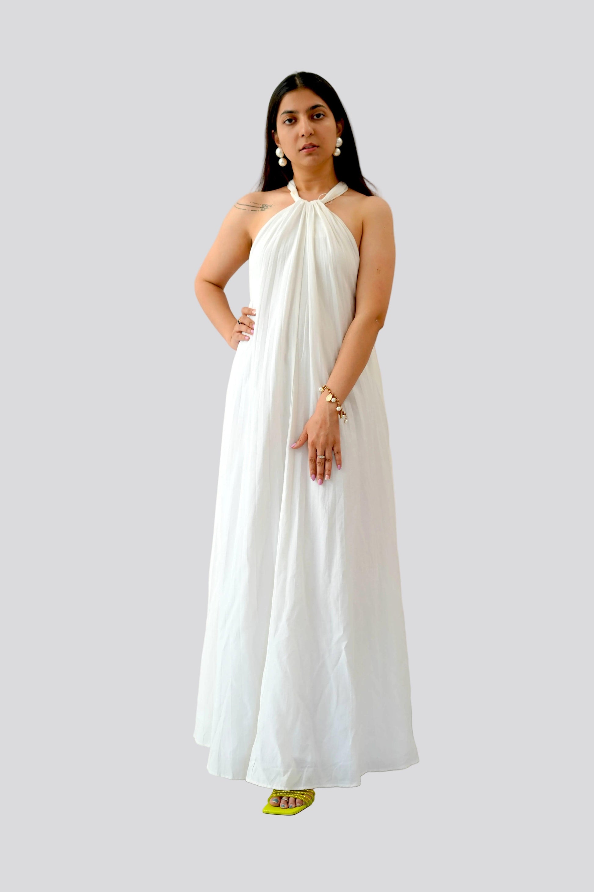 Woman wearing a white halter neck dress on a plain background
