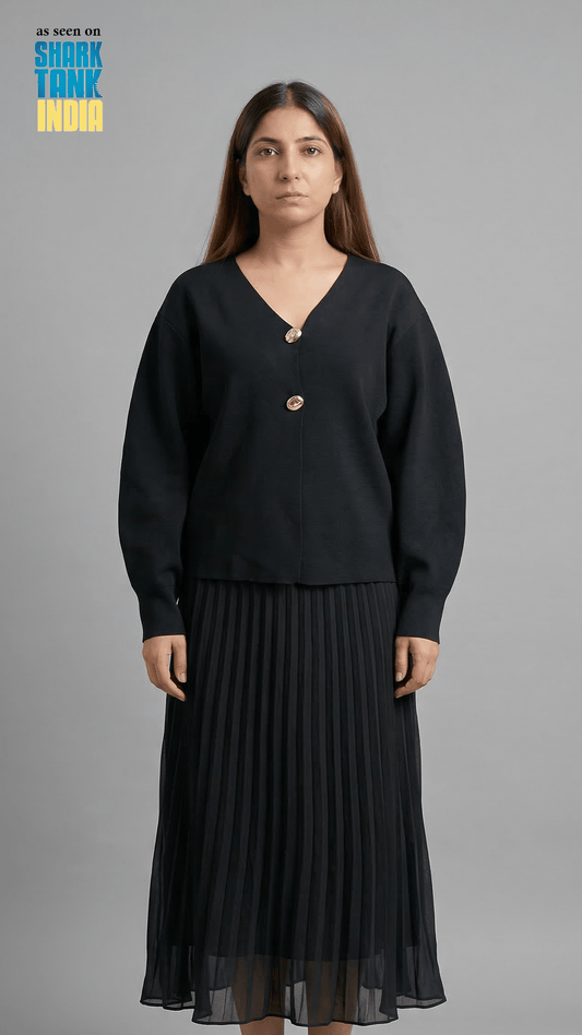 Woman wearing a black outfit with a gold button on a gray background
