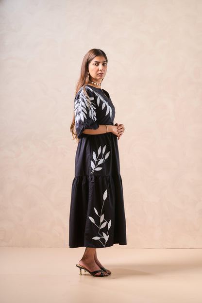 Woman wearing a black outfit with white leaf patterns on a beige background